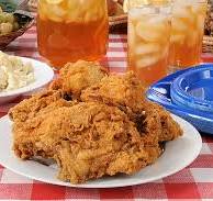 plate of fried chicken on a picnic table with ice tea