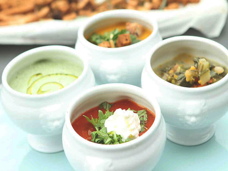 Table set with several bowls of soup of different varieties