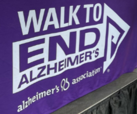 purple banner with white arrowhead on right side and white letters that read WALK TO END ALZHEIMER'S alzheimer's association