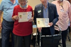 Picture of a woman and a man holding certificates and two men standing with them