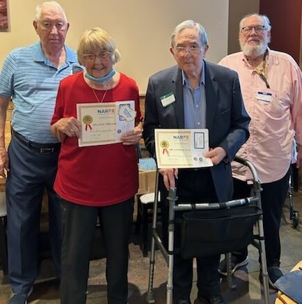 Picture of a woman and a man holding certificates and two men standing with them