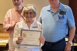 Picture of a woman holding up a certificate and two men standing by her