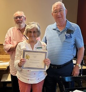Picture of a woman holding up a certificate and two men standing by her