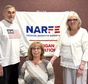 Three Chapter members standing in front of banner on a wall
