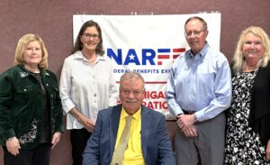 Four Chapter members standing in front of banner on a wall