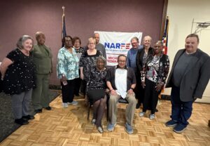 Twelve Chapter members standing in front of banner on a wall