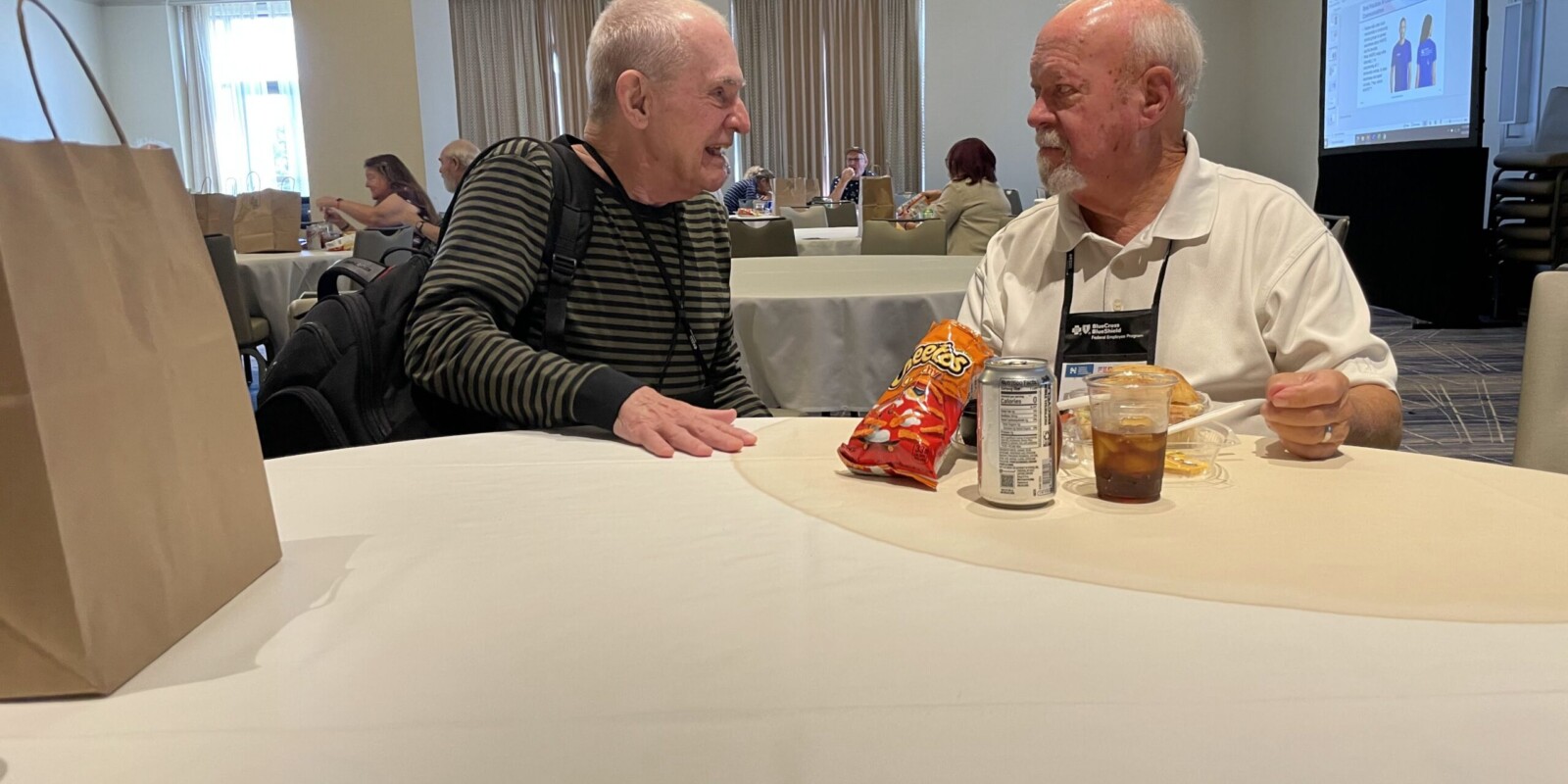 two men sitting in a room eating lunch