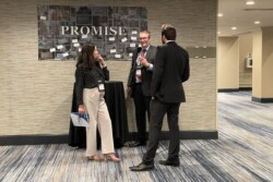 a woman and two men in a hallway in front of a board with the words Promise and multiple cards