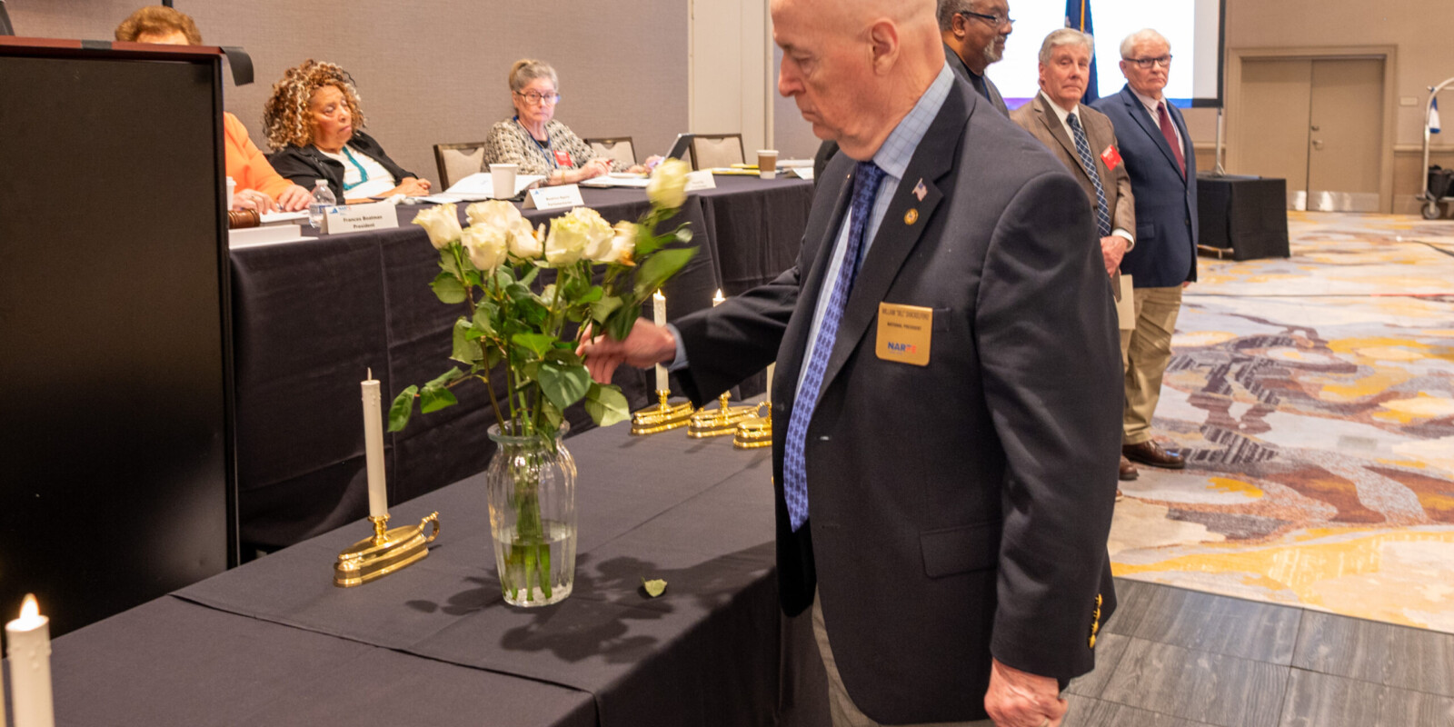NARFE President placing a white rose in the vase to remember all National Only members who dies this past year