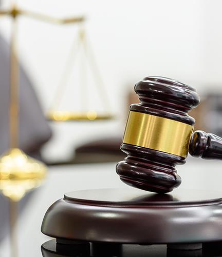 gavel resting on a block with the scale of justice blurred in the background