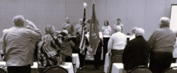 People in a meeting saluting the flag
