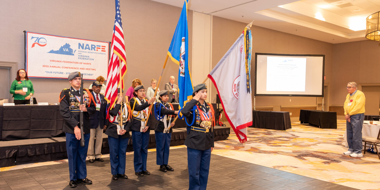 Harrisonburg Schools Honor Guard standing at attention with the U.S. Flag, the Commonwealth of Virginia Flag, and the Harrisonburg School Flag.
